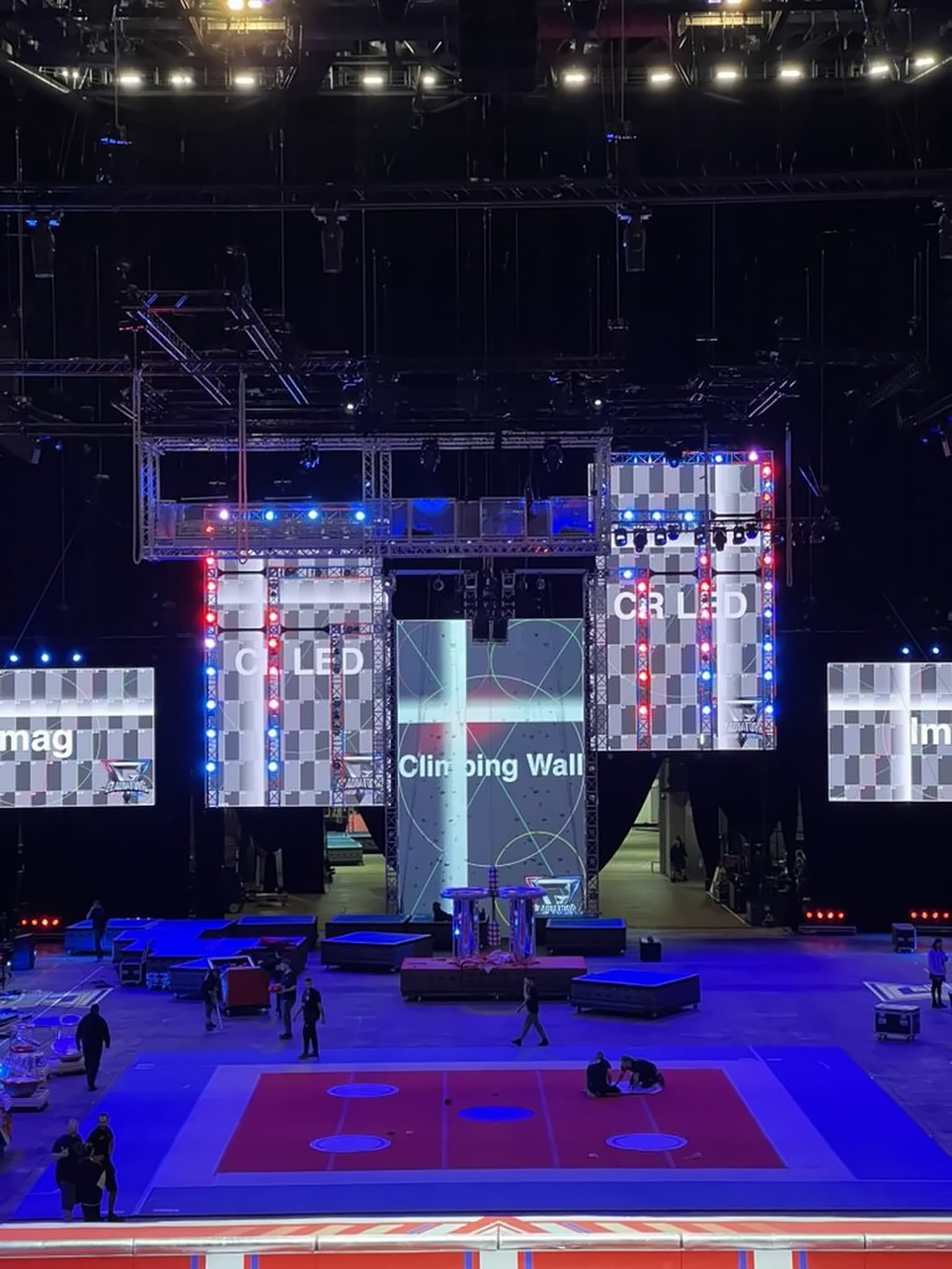Arena overview of the Gladiators Live Tour LED system: climbing wall, IMAG screens, and crew on the floor, 2025.